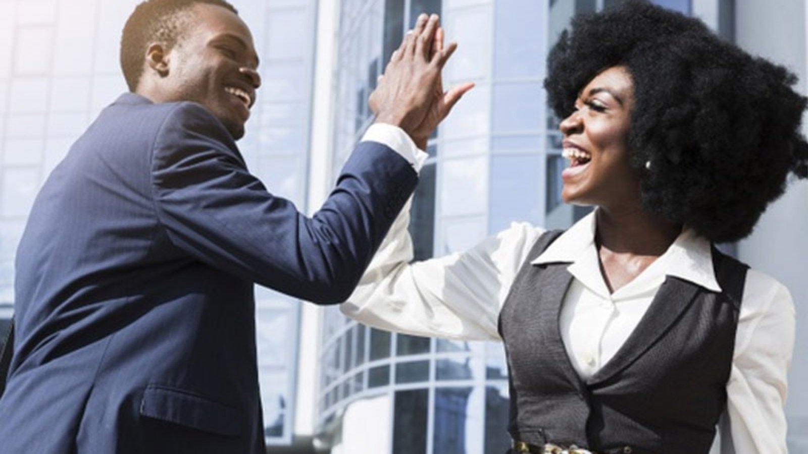 Smiling-young-businessman-and-businesswoman-giving-high-five-in-front-of-corporate-building-Free-Photo